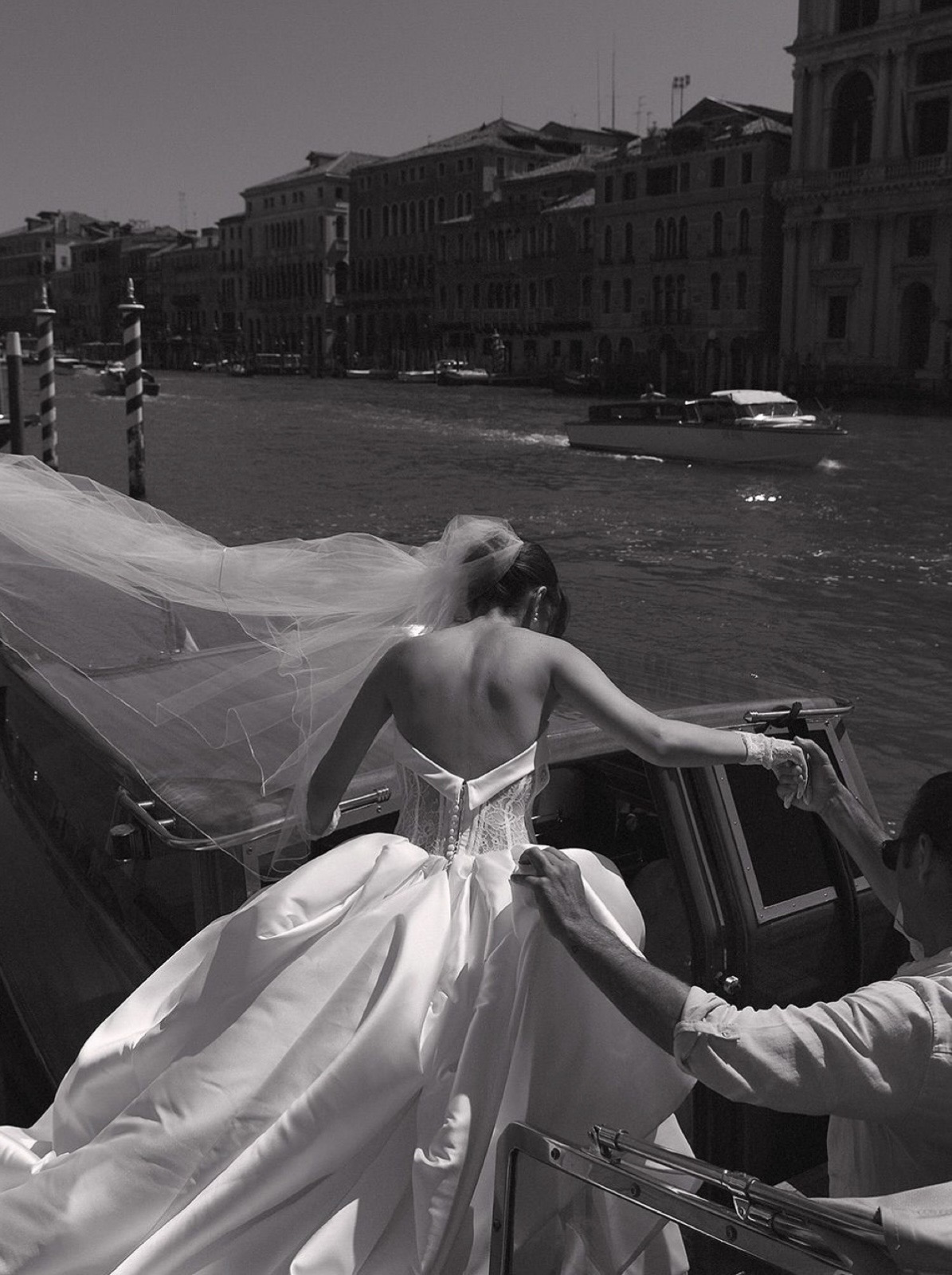 Bride in a flowing gown arriving by boat on the Venetian canals